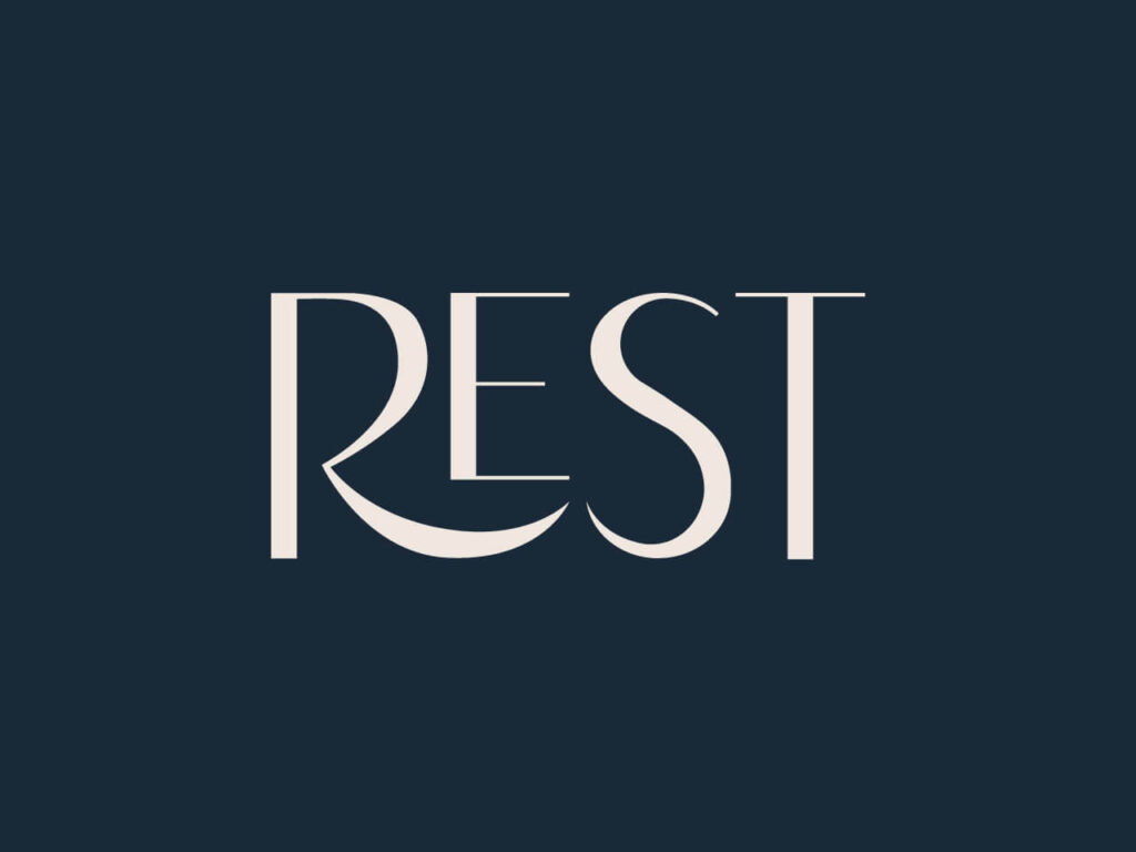 Minimalistyczne logo marki REST z elegancką typografią w kolorze kremowym na granatowym tle.
